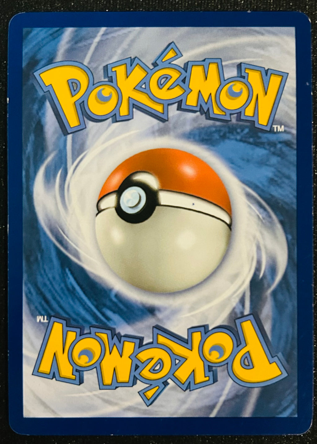 A Pokémon card back featuring the yellow Pokémon logo at the top and bottom, a large orange-and-white Pokéball centered on a blue swirling background.